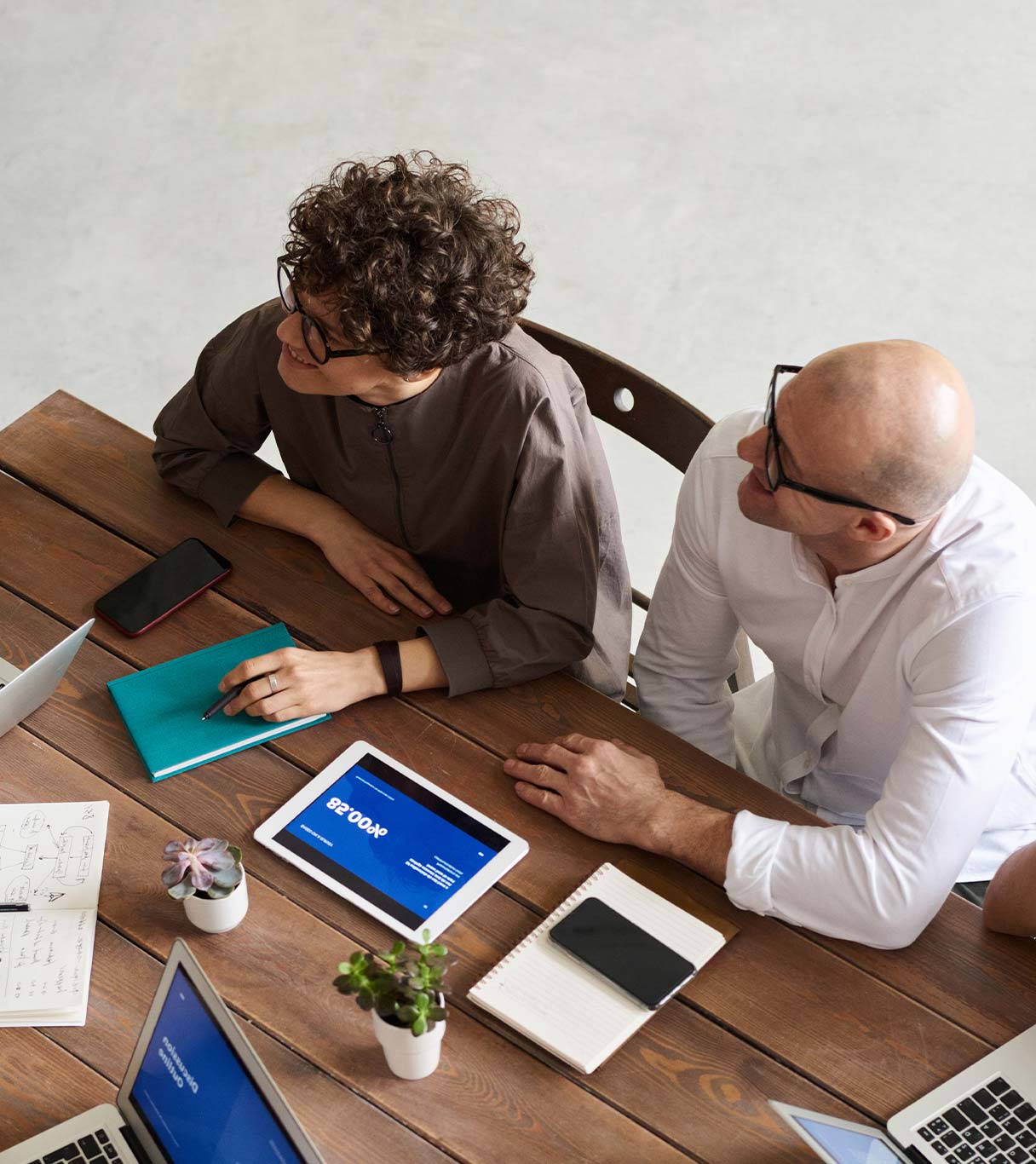 Nuevos Leaders en marketing Equipo de marketing reunido alrededor de una mesa con dispositivos digitales y notas, colaborando en una estrategia.